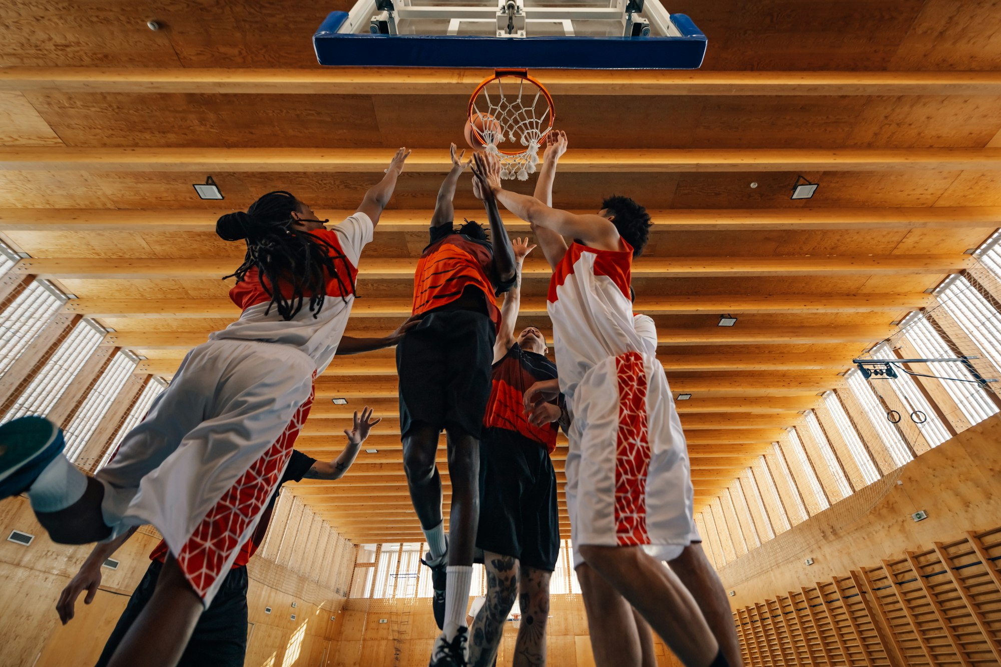 Bottom view of interracial basketball team at hoop in action on training.